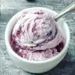 Keto Blueberry Cheesecake Ice Cream in a bowl with fresh blueberries.