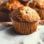 Delicious vegan banana muffins on a wooden table with fresh bananas.