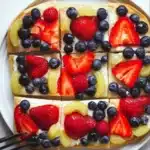 Slice of simple fruit pizza topped with fresh fruits on a cookie crust