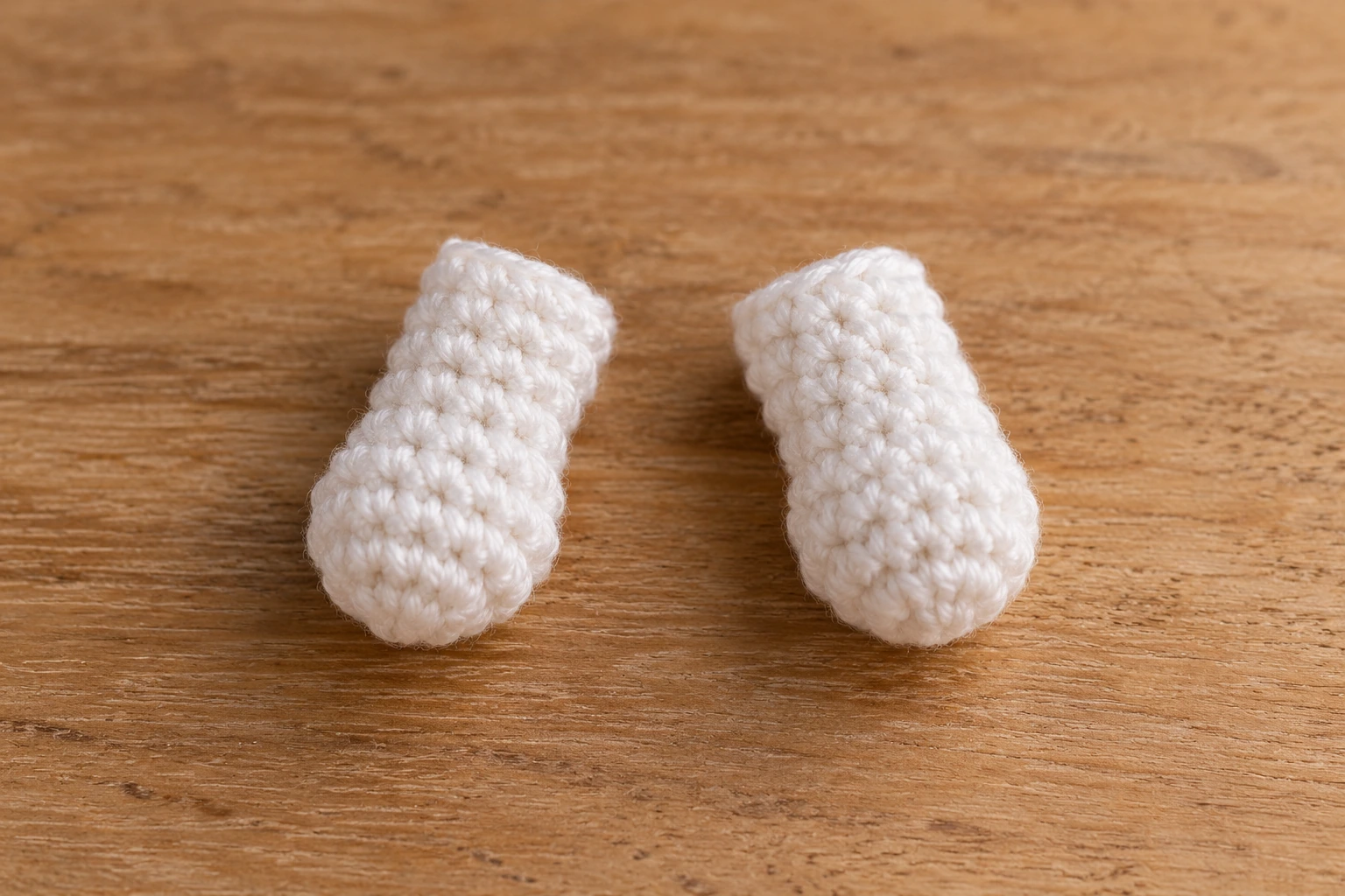 Two small white crocheted ghost hands made as short tube-like pieces